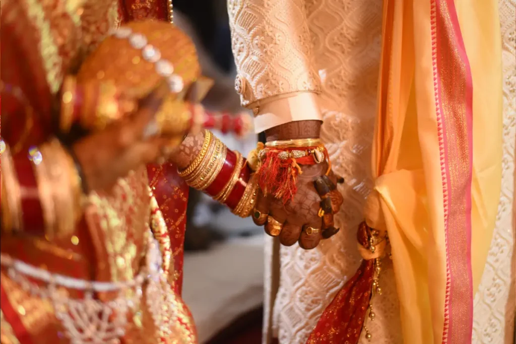 Couple holding hands in May marriage muhurat.