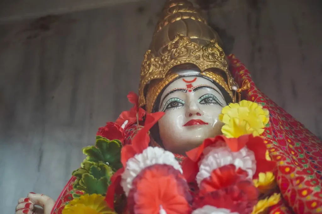 An intricately designed idol of Maa Baglamukhi, decorated with golden ornaments and flowers, representing divine power and victory as celebrated in the Baglamukhi Chalisa