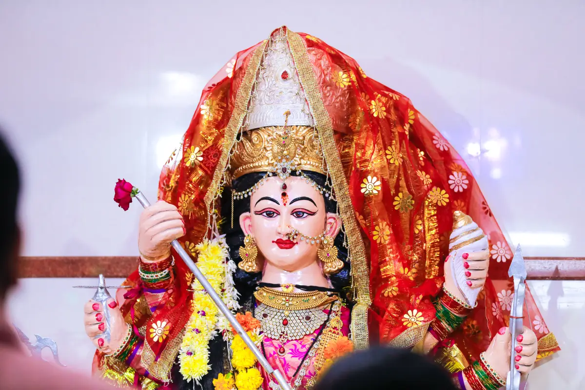 A beautifully adorned Santoshi Mata idol with floral garlands and a red veil, evoking divine grace and devotion linked to the Santoshi Mata Chalisa.