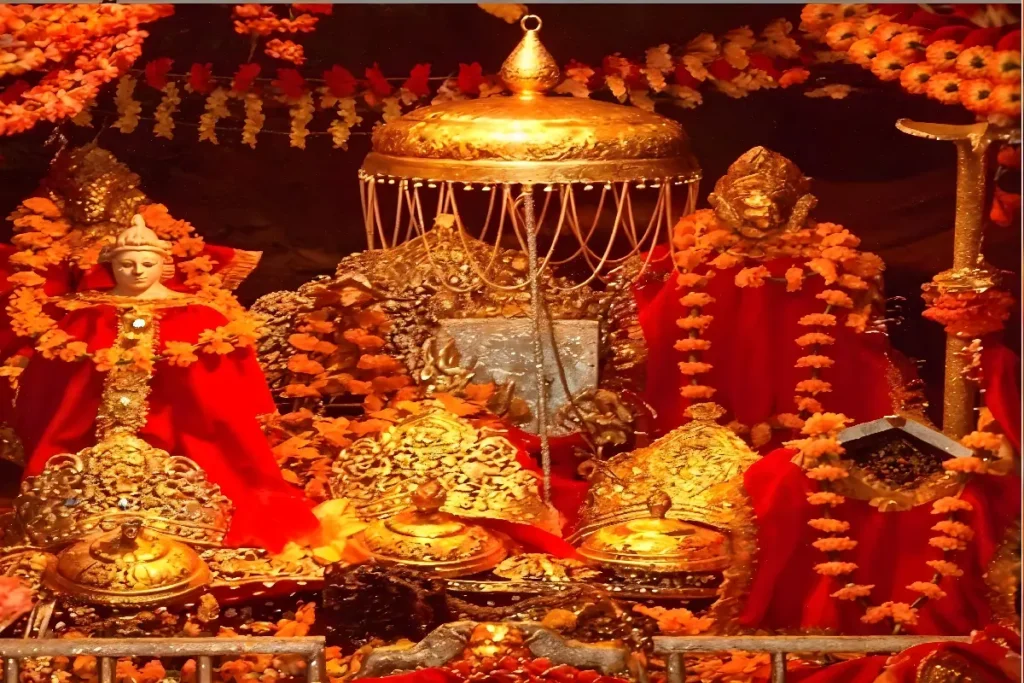 Elaborate depiction of Vaishno Devi shrine adorned with golden ornaments, vibrant red fabrics, and marigold garlands, symbolizing devotion and spiritual sanctity during a ritual setting.